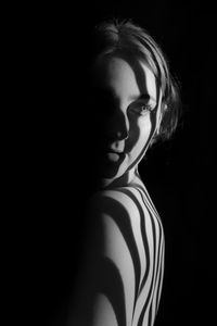 Portrait of young woman against black background