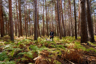 Portrait of young tattoed man with his dog in the forest