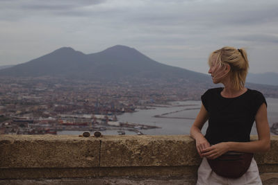 Woman looking away while leaning on retaining wall