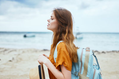 Beautiful young woman on beach against sky