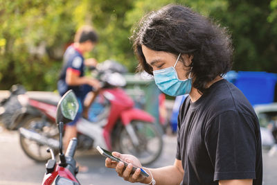 Midsection of woman holding mobile phone outdoors