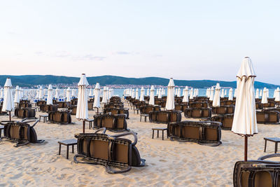 Chairs and tables on beach against sky