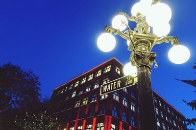 Low angle view of illuminated street light against blue sky