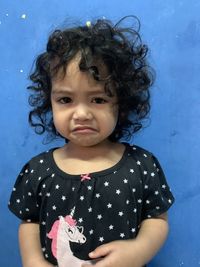 Portrait of cute girl standing against blue wall