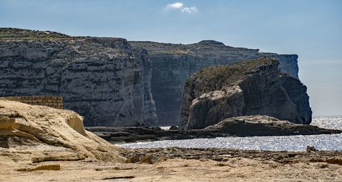 Rock formations on beach against sky