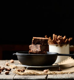 Pieces of baked brownie in a metal black frying pan on the table