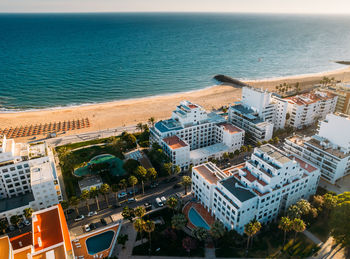 Aerial view of beach, boardwalk and buildings in quarteira, algarve, portugal on a sunny summer day