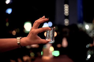 Close-up of hand using mobile phone at night