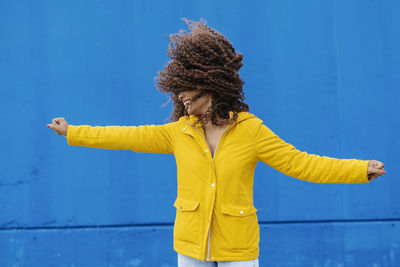 Woman with umbrella standing against blue background