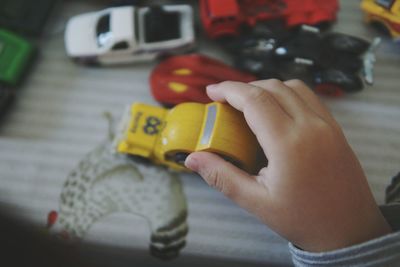 Cropped hand of child playing with toy cars at table