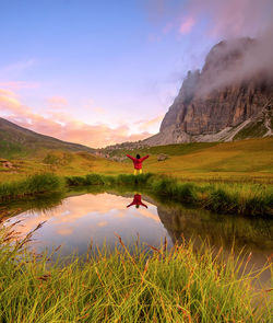 Reflection of man in lake against sky during sunset