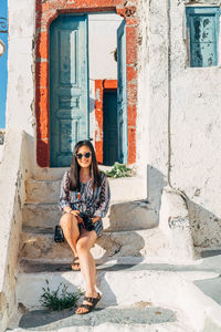 Portrait of young woman sitting on steps outside house