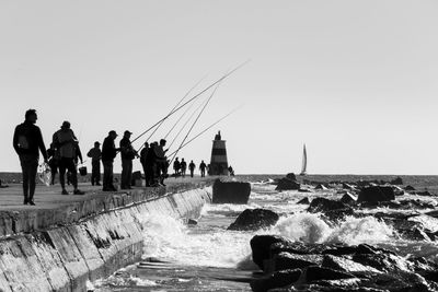 People by sea against clear sky