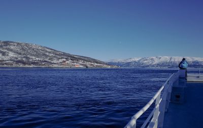 Scenic view of sea and mountains against clear blue sky