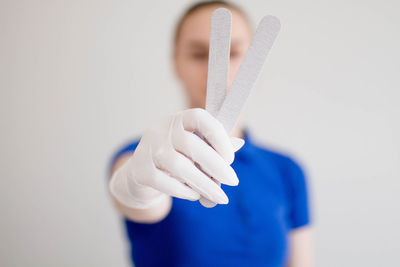 Close-up of hand holding ring against white background