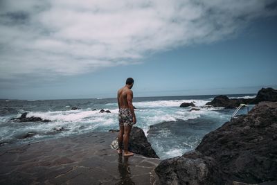 Full length of shirtless man standing on beach