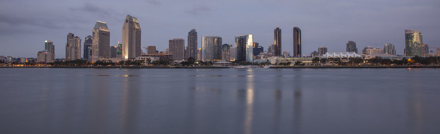 Sea by modern buildings in city against sky