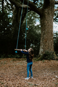 Full length of girl standing by swing