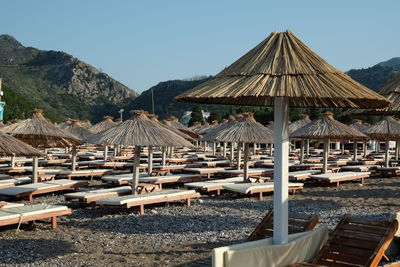 Lounge chairs on beach against clear sky