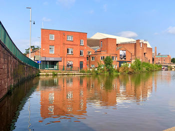 Buildings by canal against sky in city