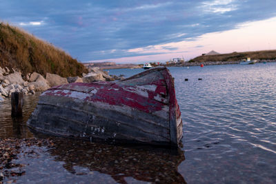 Abandoned boat on beach against sky