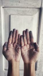 Cropped hands of person against wooden door