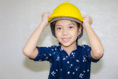 Portrait of smiling girl standing against wall