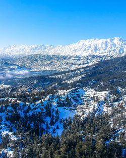 Aerial view of snowcapped mountains against blue sky