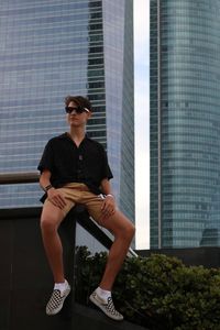 Mid adult man sitting by modern building in city