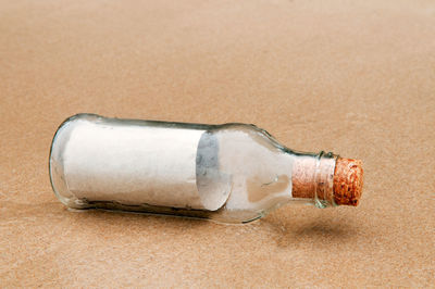 Close-up of empty glass bottle on shore