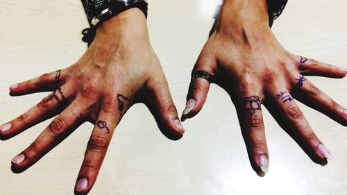 Cropped hands of woman with tattoo on table