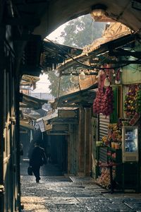 Rear view of people walking on street amidst buildings in city