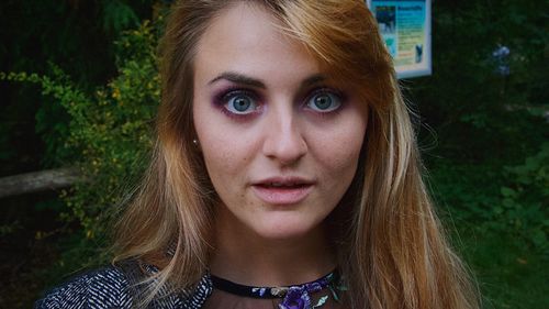 Close-up portrait of beautiful young woman against plants