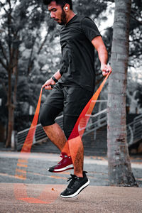 Asian sportsman training with jumping rope in the park.