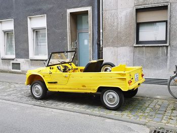 Yellow car parked on street against building