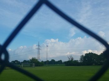 Trees on field against cloudy sky