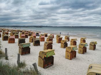 Hooded chairs on beach against sky