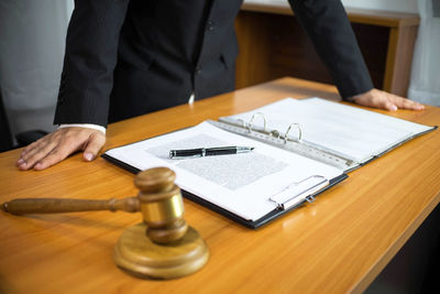 Midsection of man holding umbrella on table