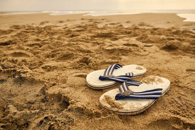 Flip-flops on a sandy beach of sea.