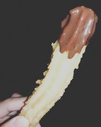 Close-up of hand holding ice cream against black background