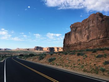 Road leading towards rock formation against sky