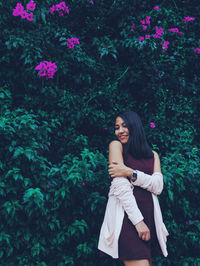 Young woman smiling while standing against plants