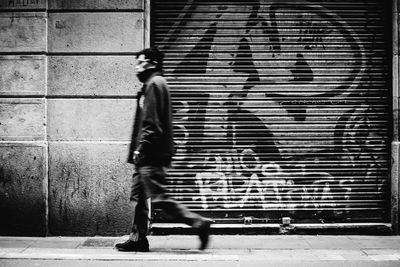 Man walking on footpath against wall