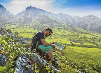 A hiker studying the map while on the path in the morning in the misty mountains.