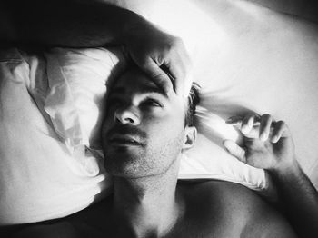 Cropped hand of gay man over male lying on bed