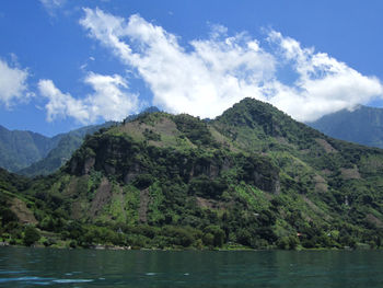 Scenic view of river and mountains against cloudy sky