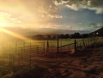 Fence on field against sky during sunset