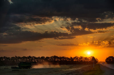 Scenic view of landscape against cloudy sky during sunset