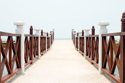 Footpath by railing against clear sky