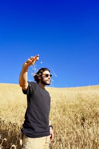 Man standing on field against clear blue sky